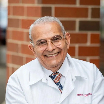 Dentist Emad Edward Azab Smiling In Front Of Brick Wall
